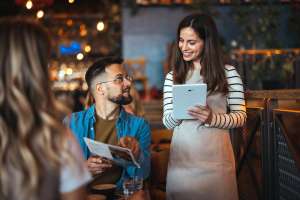 Woman taking electronic order from male customer in a restaurant