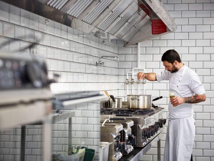 Mid adult male chef cooking food in commercial kitchen