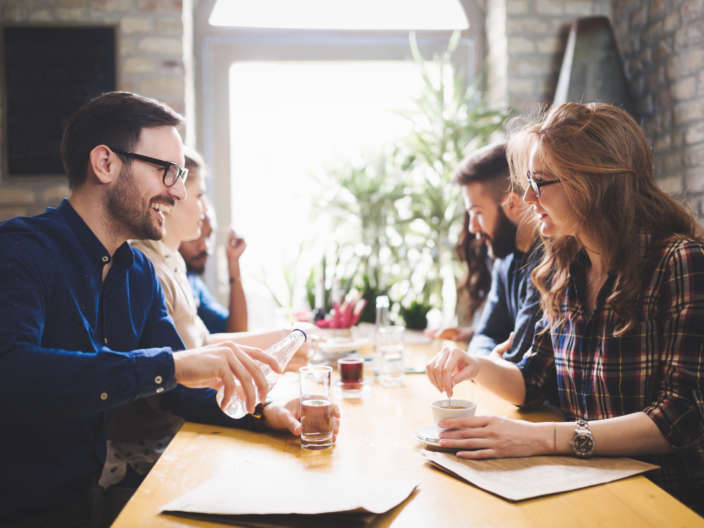 Happy colleagues from work socializing in restaurant and eating together