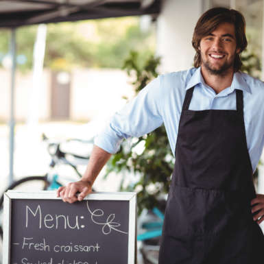 Smiling waiter standing with menu