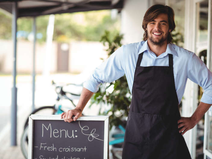 Smiling waiter standing with menu